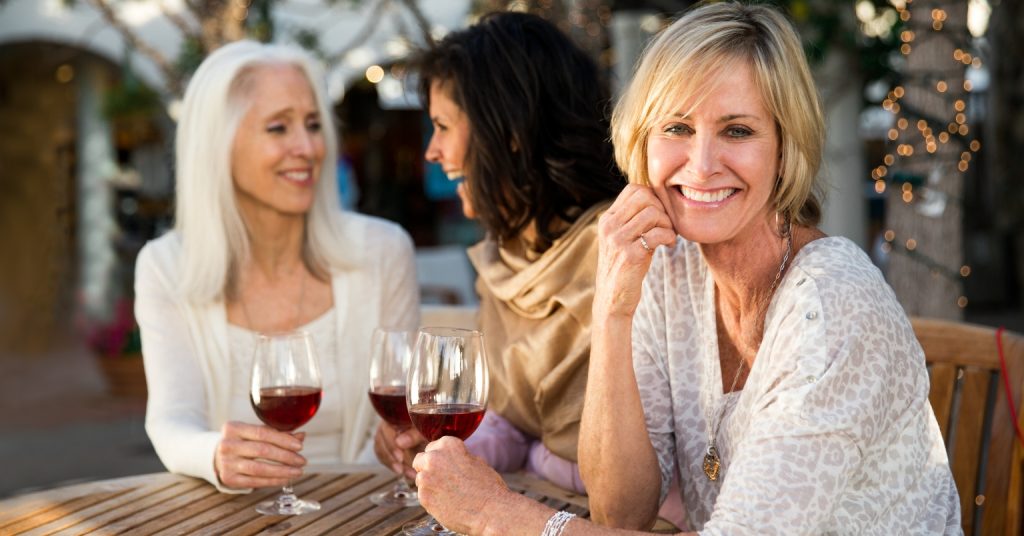 Middle-aged woman smiling and drinking wine