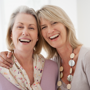 Two women smiling as they prep for plastic surgery