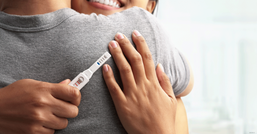 Woman with positive pregnancy test hugging man