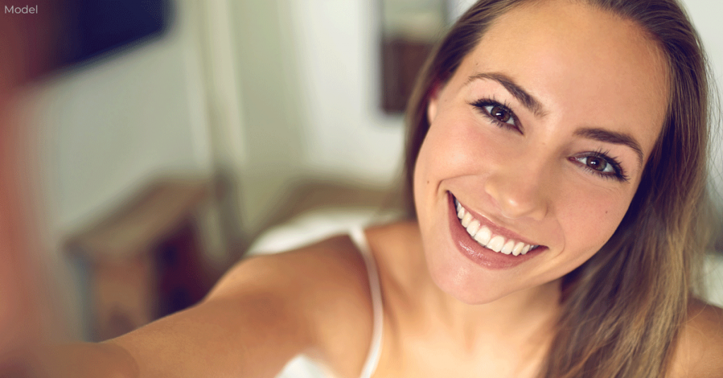 Young woman taking a selfie after eyelid surgery