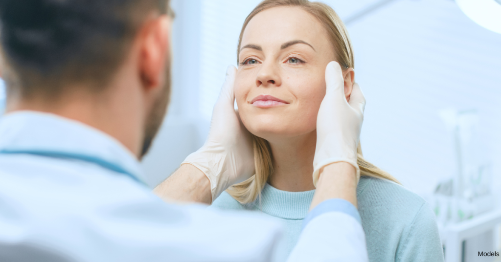 Male doctor holding female patient's face for an exam (models)