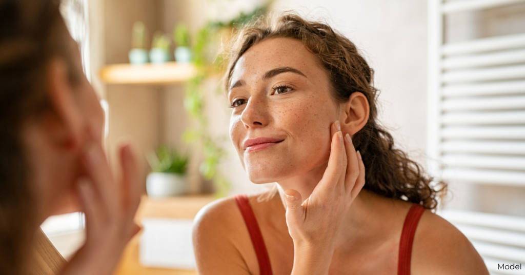 Woman (model) examining her face in the mirror.