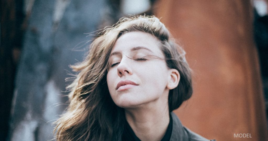 Young woman closing her eyes, enjoying the sun on her face